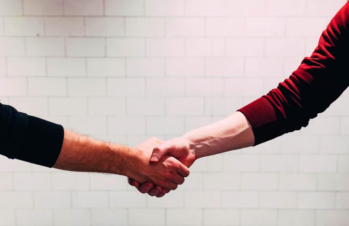 Two men shaking hands after making a deal flipping money