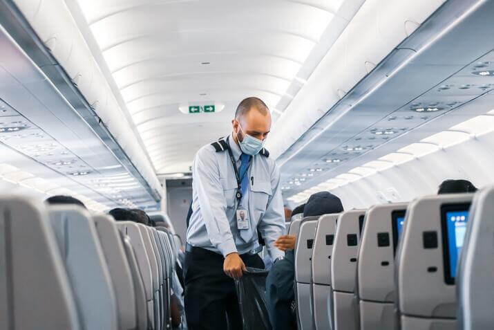A flight attendant taking trash. Not a job well suited for introverts